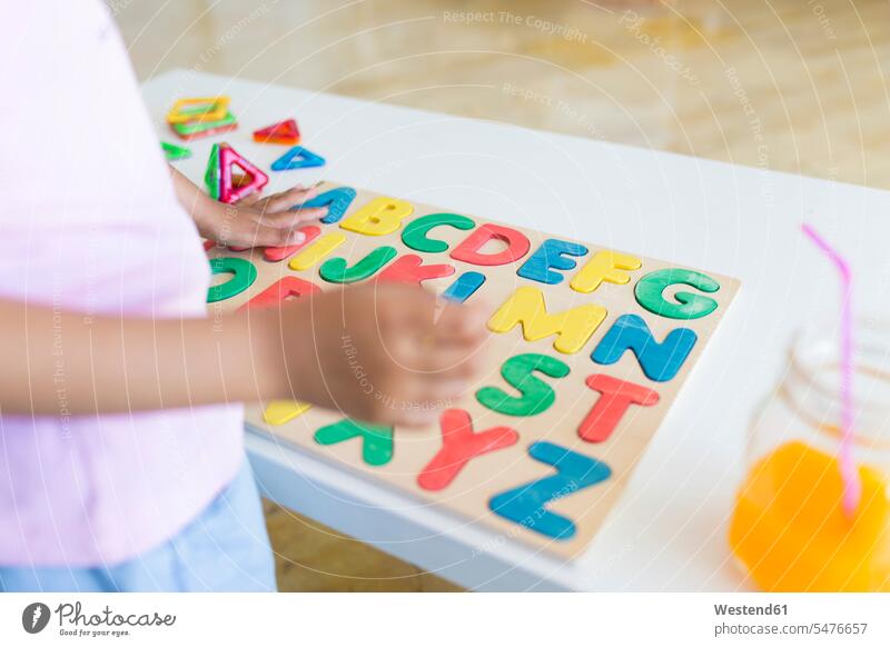 Nahaufnahme eines Mädchens, das mit einem Alphabet-Lernspiel auf dem Tisch spielt Leute Menschen People Person Personen gemischtrassig 1 Ein ein Mensch