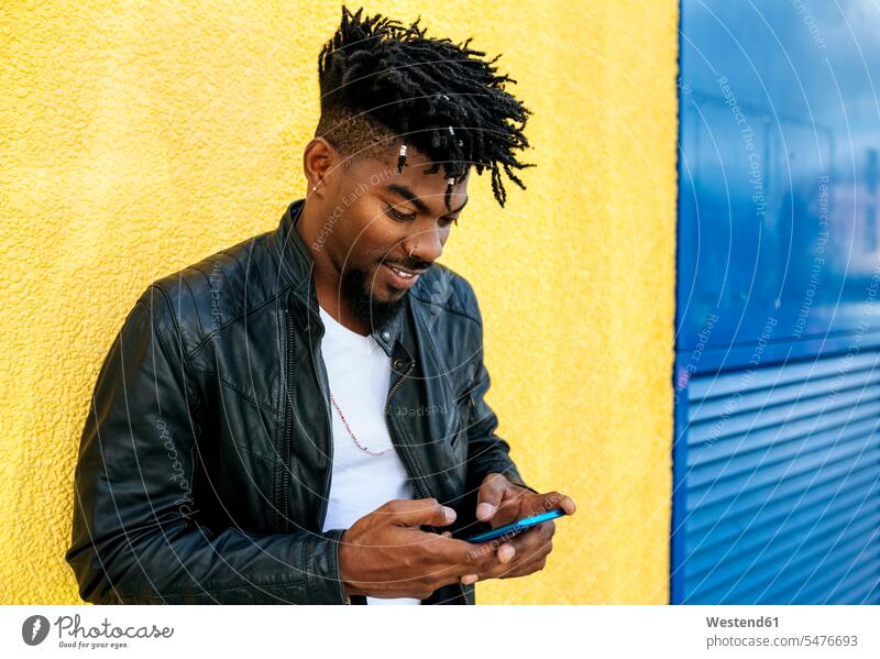 Nahaufnahme eines mittelgroßen erwachsenen Mannes mit Ortungsgeräten mit Mobiltelefon, während er an der Wand steht Farbaufnahme Farbe Farbfoto Farbphoto
