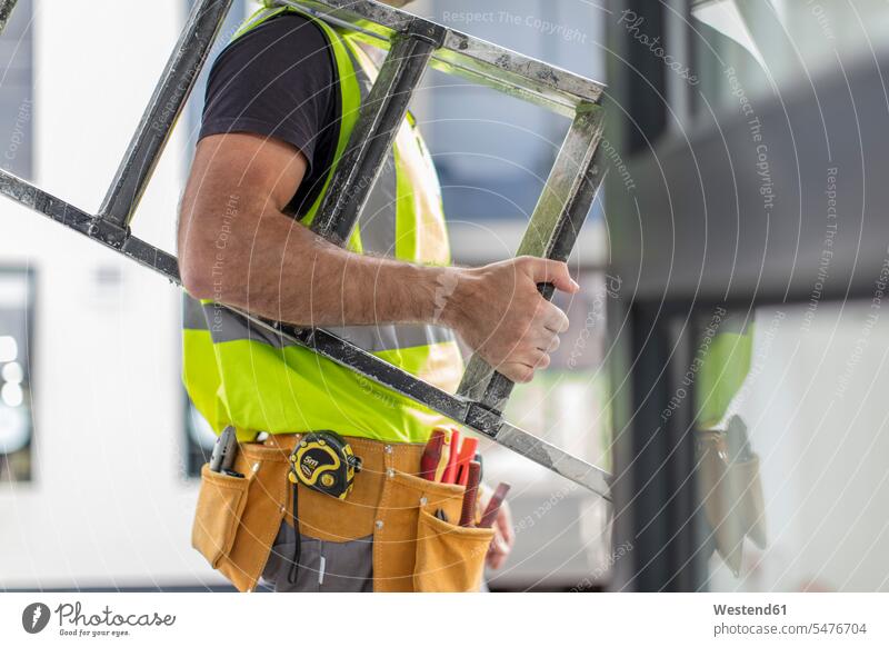 Nahaufnahme eines Bauarbeiters, der eine Leiter trägt Leitern arbeiten Arbeit tragen transportieren Handwerker Handwerksberuf Handwerksberufe Gewerbe Europäer