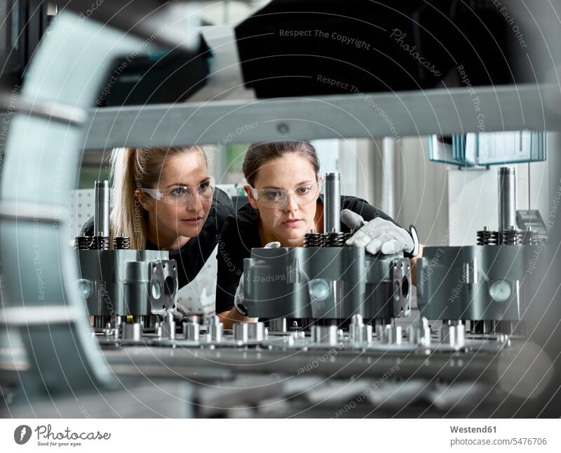 Junge Frauen bei der Kontrolle einer Produktionslinie am Fließband prüfender Blick genaue Untersuchung untersuchen betrachten Schutzbrille Schutzbrillen Brille