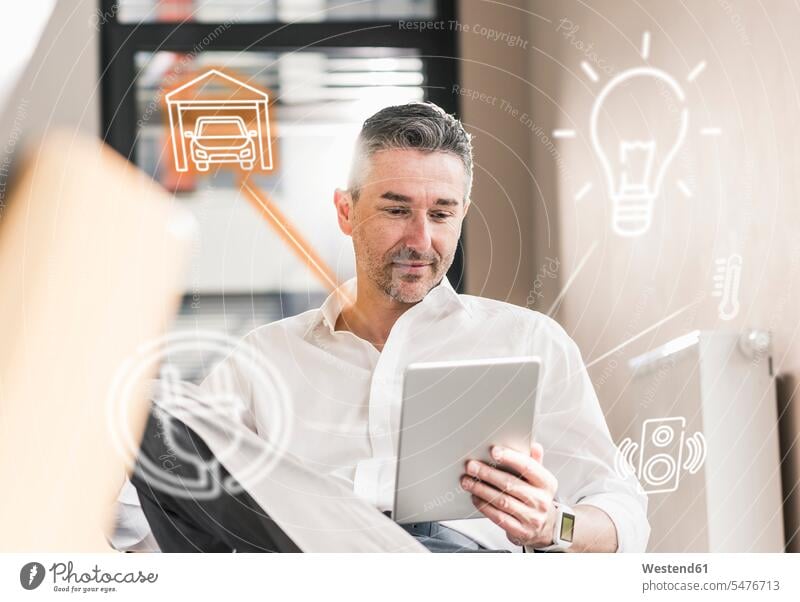 Mann sitzt im Büro und benutzt ein digitales Tablet zur Fernsteuerung seines intelligenten Hauses Männer männlich einschalten anschalten Office Büros Smart Home