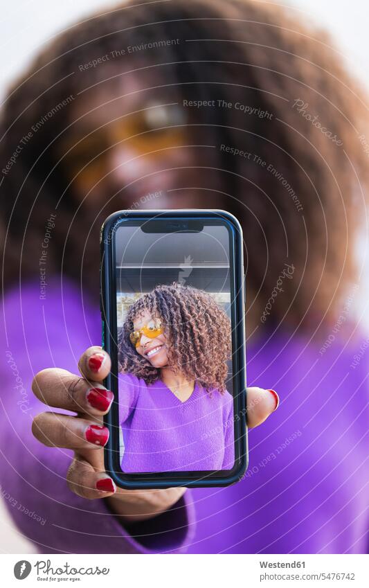 Afro-Frau zeigt Selfie durch Mobiltelefon Farbaufnahme Farbe Farbfoto Farbphoto Außenaufnahme außen draußen im Freien Tag Tageslichtaufnahme Tageslichtaufnahmen
