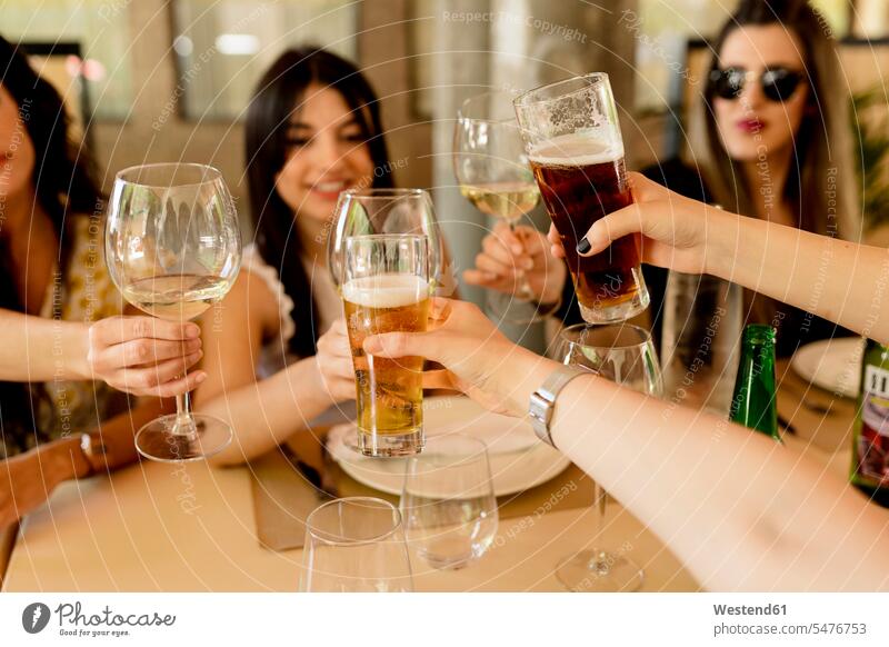 Glückliche Freundinnen stoßen im Restaurant am Tisch auf Getränke an Farbaufnahme Farbe Farbfoto Farbphoto Spanien Innenaufnahme Innenaufnahmen drinnen Tag