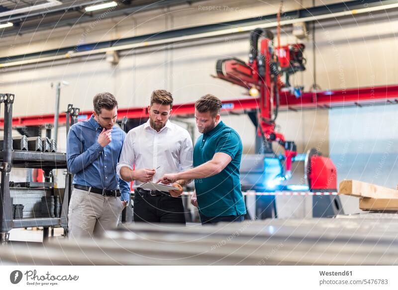 Drei Männer teilen sich Tabletten in der Fabrikhalle Teilen Sharing Mann männlich Produktionshalle Montagehalle Kollegen Arbeitskollegen Fabriken