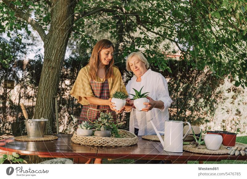 Mutter und Tochter halten Topfpflanzen, während sie am Tisch im Hof stehen Farbaufnahme Farbe Farbfoto Farbphoto Spanien Freizeitbeschäftigung Muße Zeit