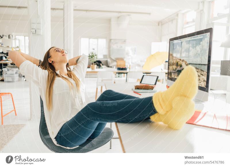 Junger Freiberufler entspannt mit den Füßen am Schreibtisch in einem Loft freiberuflich freie Berufe Arbeitstisch Schreibtische Lofts Entspannung Entspannen
