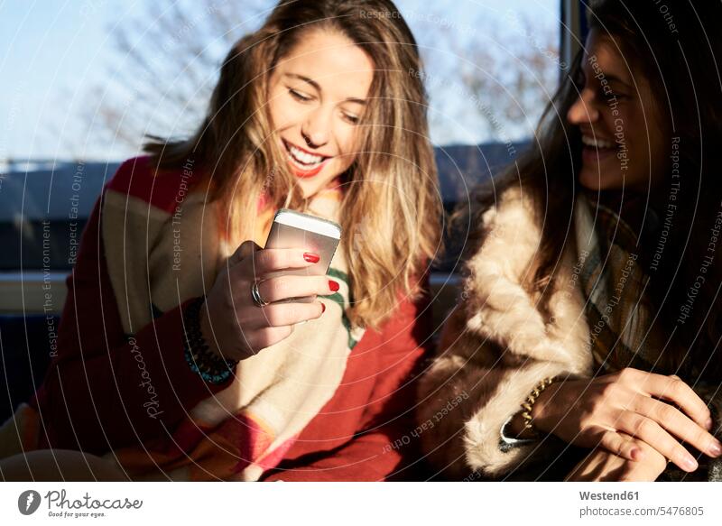 UK, London, zwei glückliche Frauen in U-Bahn-Zug mit Handy Freundinnen Ubahn U-Bahnen Untergrundbahnen Ubahnen Underground Subway Mobiltelefon Handies Handys