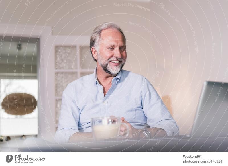 Porträt eines glücklichen Mannes, der auf einen Laptop schaut Portrait Porträts Portraits schauen schauend anschauen betrachten Männer männlich Notebook Laptops