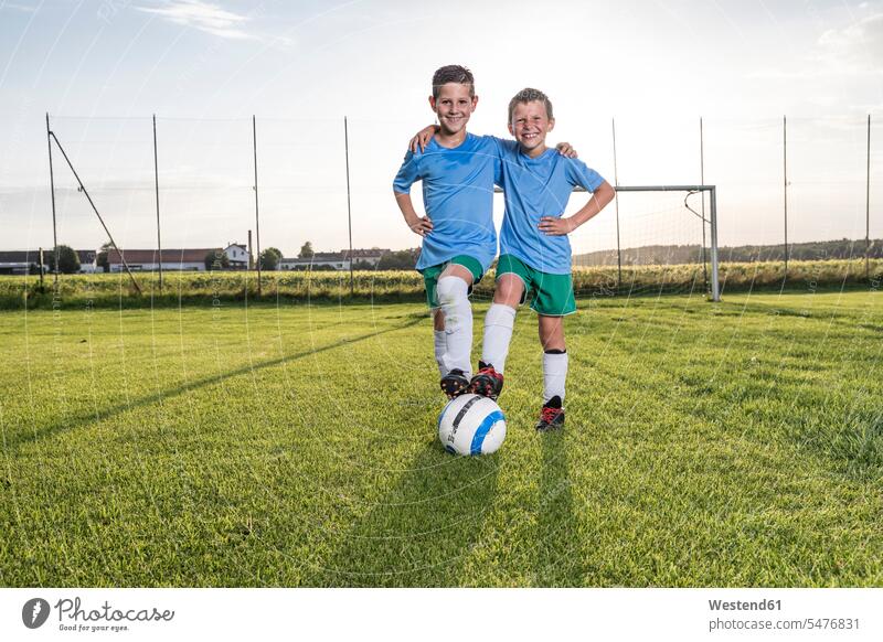 Lächelnde junge Fussballspieler umarmen sich auf dem Fussballplatz Umarmung Umarmungen Arm umlegen lächeln Fußballspieler Fussballer Fußballer Fußballplatz