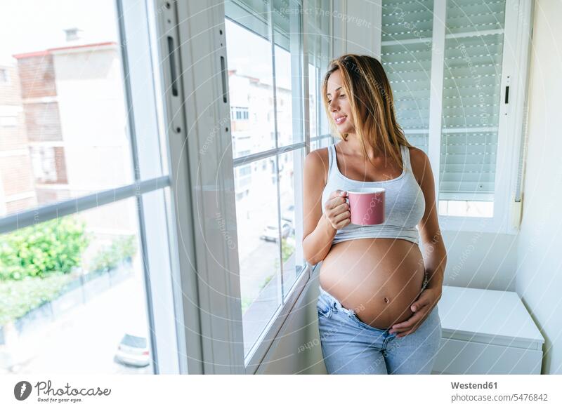 Schwangere Frau schaut aus dem Fenster und hält einen Becher weiblich Frauen halten schwanger schwangere Frau Erwachsener erwachsen Mensch Menschen Leute People
