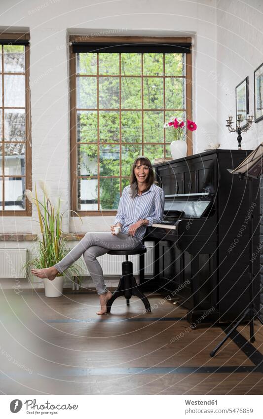 Frau sitzt am Klavier und trinkt Kaffee trinken Zuhause zu Hause daheim weiblich Frauen sitzen sitzend Piano Pianos Klaviere Erwachsener erwachsen Mensch