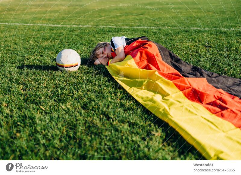 Junge schläft auf Fußballfeld, mit deutscher Fahne bedeckt Fußballtrikot Fußballtrikots Fussballtrikot Fussballtrikots Buben Knabe Jungen Knaben männlich