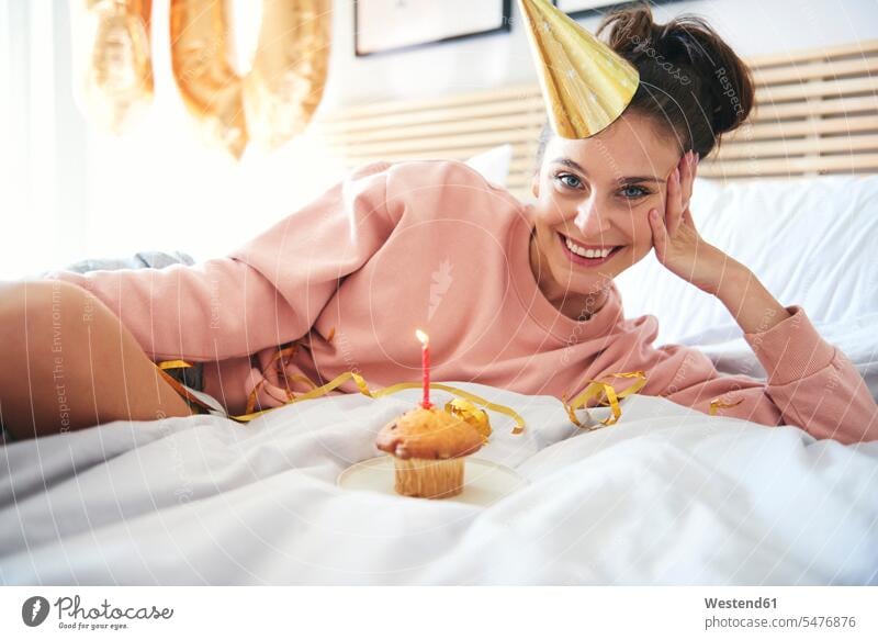 Glückliche junge Frau mit Cupcake während Geburtstag Bett Betten Muffin Muffins Allein alleine einzeln glücklich glücklich sein glücklichsein weiblich Frauen