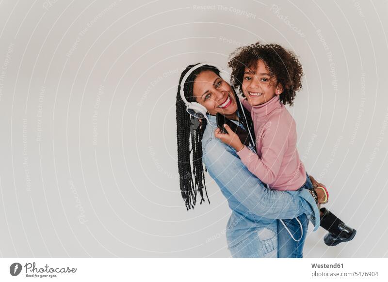 Porträt einer glücklichen Mutter und ihrer kleinen Tochter Kopfhoerer Handies Handys Mobiltelefon Mobiltelefone entspannen relaxen hoeren freuen Frohsinn