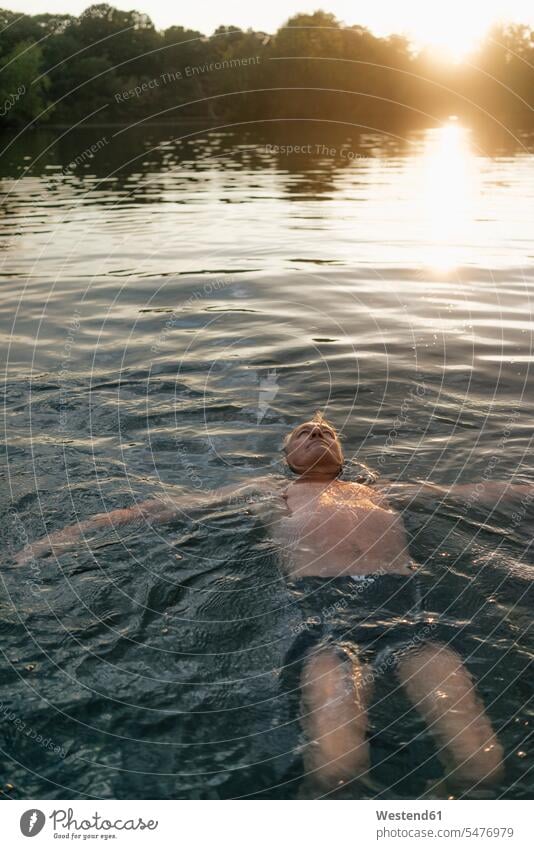 Senior Mann schwimmen in einem See bei Sonnenuntergang Seen Sonnenuntergänge Männer männlich ältere Männer älterer Mann Senioren Gewässer Wasser Stimmung