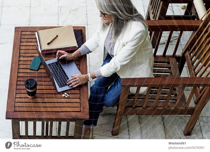 Unternehmerin benutzt Laptop, während sie im Garten an einem Holztisch sitzt Farbaufnahme Farbe Farbfoto Farbphoto Spanien Außenaufnahme außen draußen im Freien