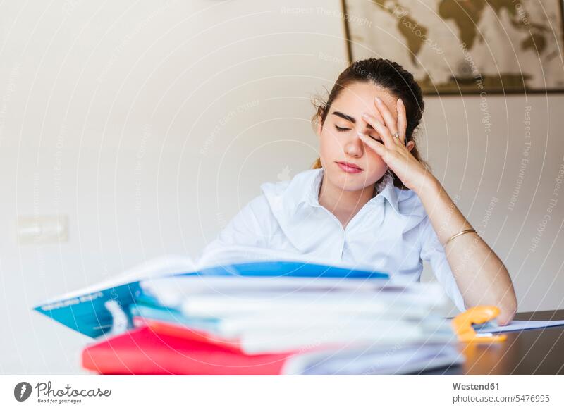 Frustrierte Studentin mit Unterlagen am Schreibtisch zu Hause Papier lernen sitzen studieren Pessimismus Zuhause Frustration Prüfung Stress Wissen Vorderansicht