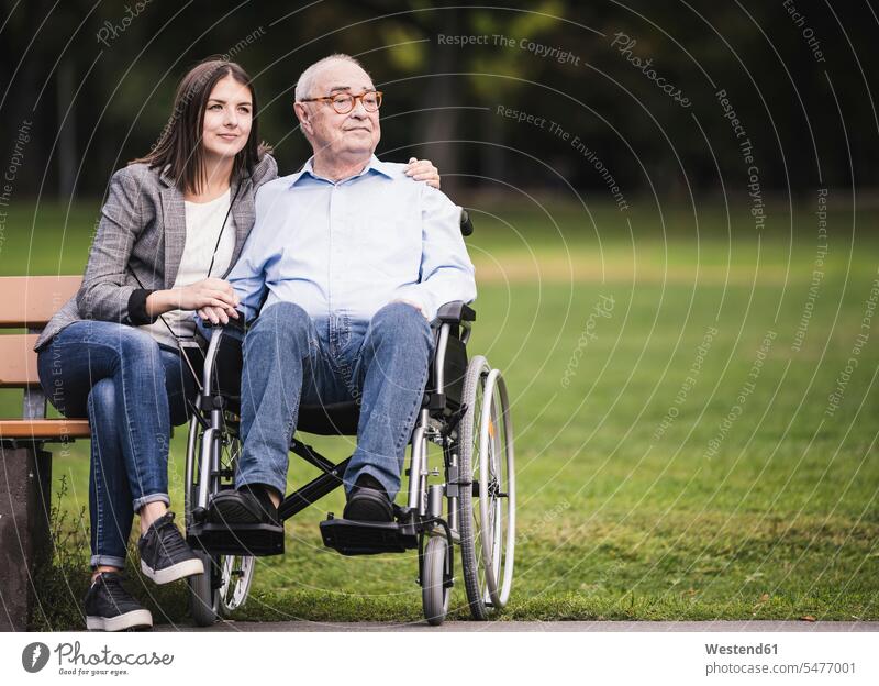 Porträt eines älteren Mannes im Rollstuhl, der sich mit seiner Enkelin in einem Park entspannt Generation entspannen relaxen sitzend sitzt gefühlvoll Emotionen
