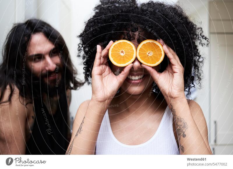Glückliche junge Frau bedeckt ihre Augen mit Orangen in der Küche bedecken abdecken zudecken Paar Pärchen Paare Partnerschaft glücklich glücklich sein