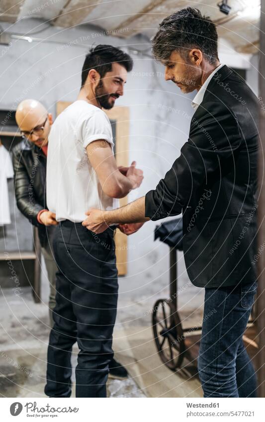Zwei Männer arbeiten an neuem stilvollen Look für gut aussehenden Mann im Ausstellungsraum Kunde Kunden Kundschaft Herrenmode männlich Geschäft Shop Laden Läden
