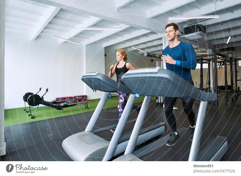 Mann und Frau laufen im Fitnessstudio auf dem Laufband Fitnessclubs Fitnessstudios Turnhalle Männer männlich weiblich Frauen Laufbaender Laufbänder rennen fit