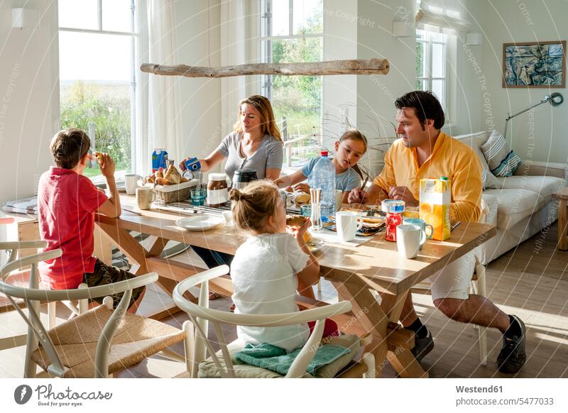 Familie beim Frühstück am Esstisch Stuehle Stühle sitzend sitzt früh Frühe Morgen Jahreszeiten sommerlich Sommerzeit geniessen Genuss daheim zu Hause