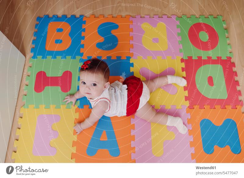 Süßes Mädchen liegt zu Hause auf einer bunten Puzzle-Spielmatte Farbaufnahme Farbe Farbfoto Farbphoto Spanien Innenaufnahme Innenaufnahmen innen drinnen