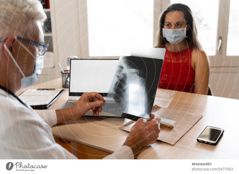Arzt sieht sich medizinisches Röntgenbild eines menschlichen Halses an, während er in der Klinik sitzt Farbaufnahme Farbe Farbfoto Farbphoto Innenaufnahme