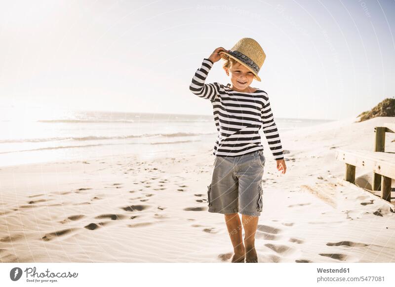 Porträt eines lächelnden Jungen mit Hut am Strand Hüte gehend geht Jahreszeiten sommerlich Sommerzeit freuen geniessen Genuss Glück glücklich sein glücklichsein