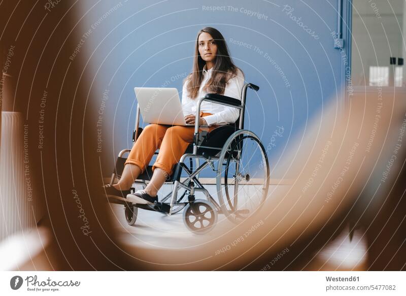 Junge behinderte Frau, die im Rollstuhl sitzt und einen Laptop benutzt weiblich Frauen Zuversicht Zuversichtlich Selbstvertrauen selbstbewusst Vertrauen ernst