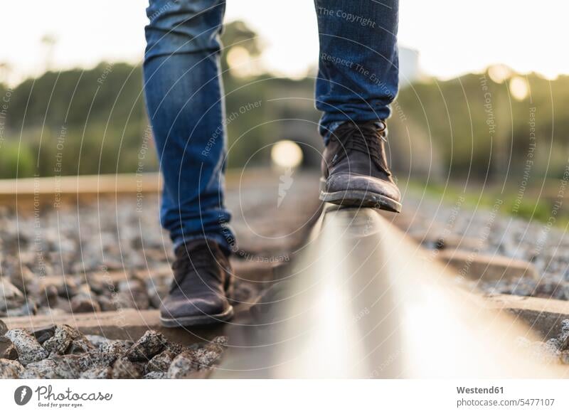 Junger Mann steht auf Eisenbahnschiene Gleis Eisenbahngleise Geleise Gleise Schiene Bahngleis Bahngleise Schienen Männer männlich standhaft Schuh Schuhe stehen