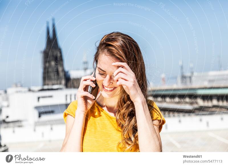 Deutschland, Köln, lächelnde Frau am Telefon weiblich Frauen telefonieren anrufen Anruf telephonieren Erwachsener erwachsen Mensch Menschen Leute People