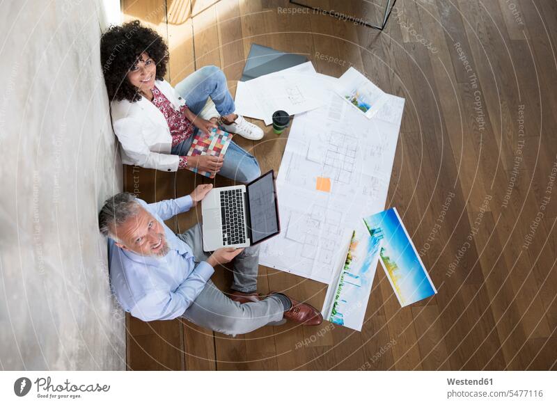 Geschäftsmann und Geschäftsfrau sitzen auf dem Boden in einem Loft arbeiten mit Laptop und Dokumente Notebook Laptops Notebooks Lofts sitzend sitzt Arbeit