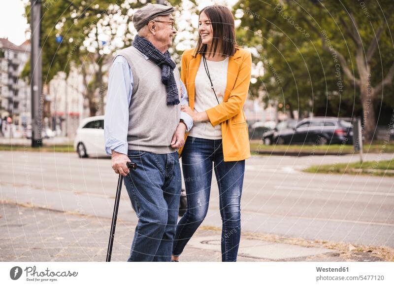 Erwachsene Enkelin hilft ihrem Großvater beim Spaziergang mit einem Spazierstock Leute Menschen People Person Personen Europäisch Kaukasier kaukasisch 2