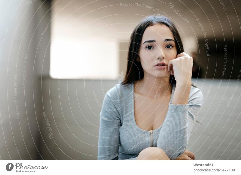 Porträt einer nachdenklichen Frau Kleider sitzend sitzt vereinsamt zurueckgezogen zurückgezogen graue grauer graues alleine einzeln Attraktivität gut aussehend