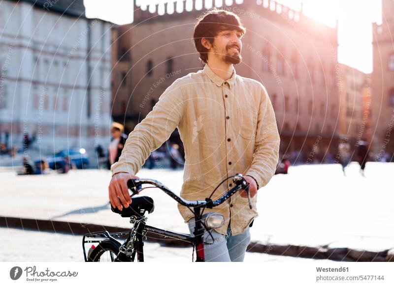 Italien, Bologna, Porträt eines entspannten jungen Mannes, der in der Stadt Fahrrad fährt Männer männlich Portrait Porträts Portraits Bikes Fahrräder Räder Rad
