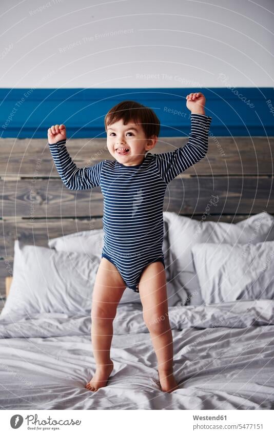 Porträt eines glücklichen Kleinkindes, das auf das Bett springt Glück glücklich sein glücklichsein Junge männliche Babys männliches Baby männliche Babies Betten