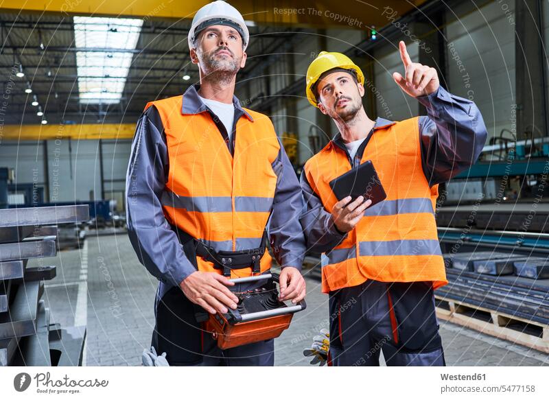 Zwei Männer in der Fabrik sprechen und bedienen Maschinen mit Fernkonsole Mann männlich fernsteuern Konsole Fabrikgebäude Fabrikgebaeude Fabriken reden