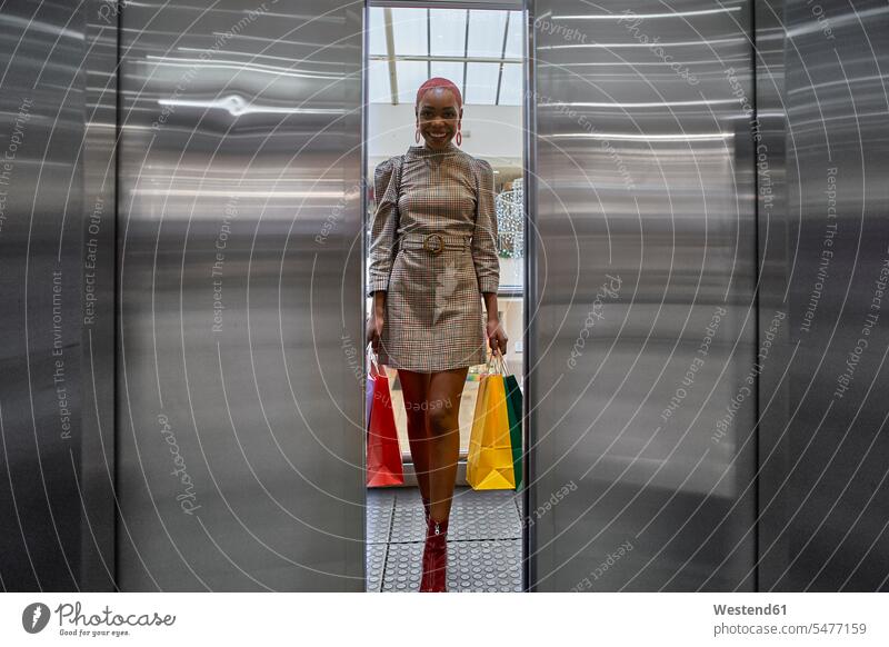 Frau mit bunten Einkaufstaschen am Aufzug Leute Menschen People Person Personen Afrikanisch Afrikanische Abstammung dunkelhäutig Farbige Farbiger Schwarze 1