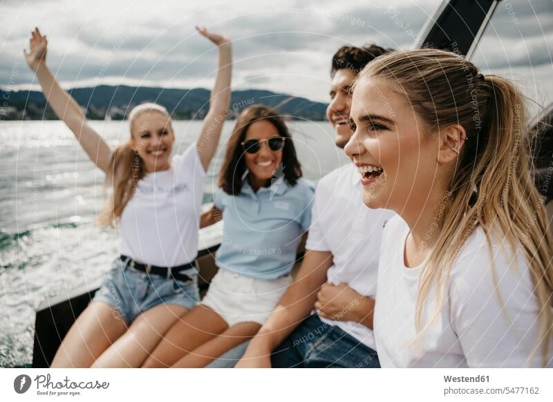 Glückliche Freunde bei einer Bootsfahrt auf einem See Kameradschaft Freundin T-Shirts Wasserfahrzeug Boote Motorboote sitzend sitzt Jahreszeiten sommerlich