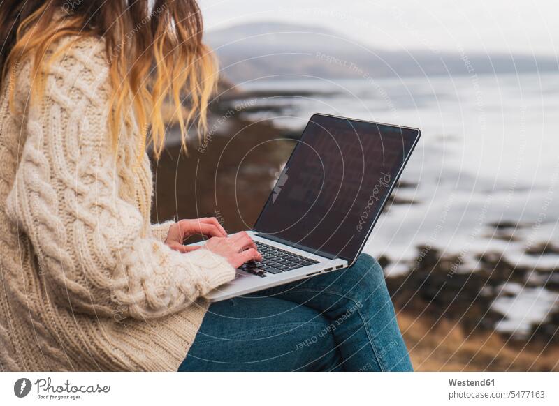 Island, Frau mit Laptop an der Küste weiblich Frauen Kueste Kuesten Küsten Republik Island Notebook Laptops Notebooks Erwachsener erwachsen Mensch Menschen