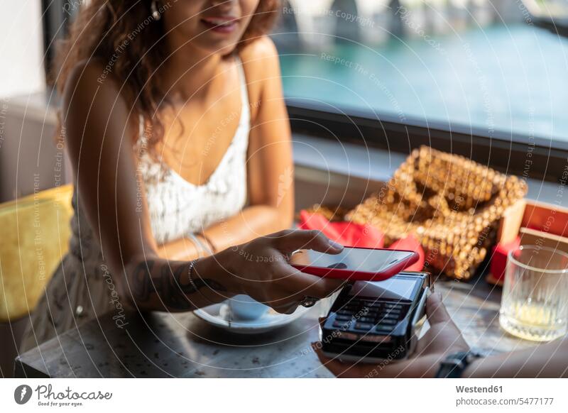 Junge Frau bezahlt Rechnung mit Smartphone im Café Touristen Bedienung Bedienungspersonal Service Kellner Ober Kellnerinnen Restaurantfachfrau Gläser Trinkglas
