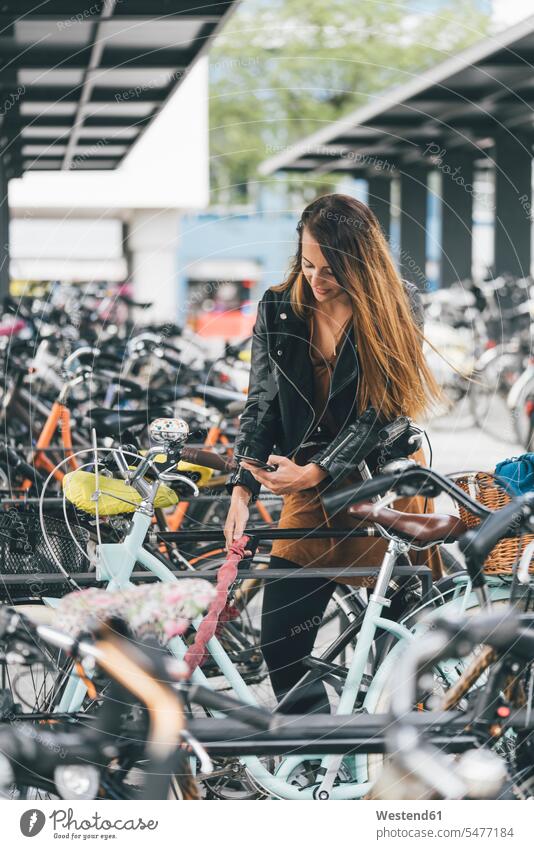 Junge Frau mit Fahrrad, die in der Stadt mit dem Handy telefoniert weiblich Frauen staedtisch städtisch Mobiltelefon Handies Handys Mobiltelefone Bikes