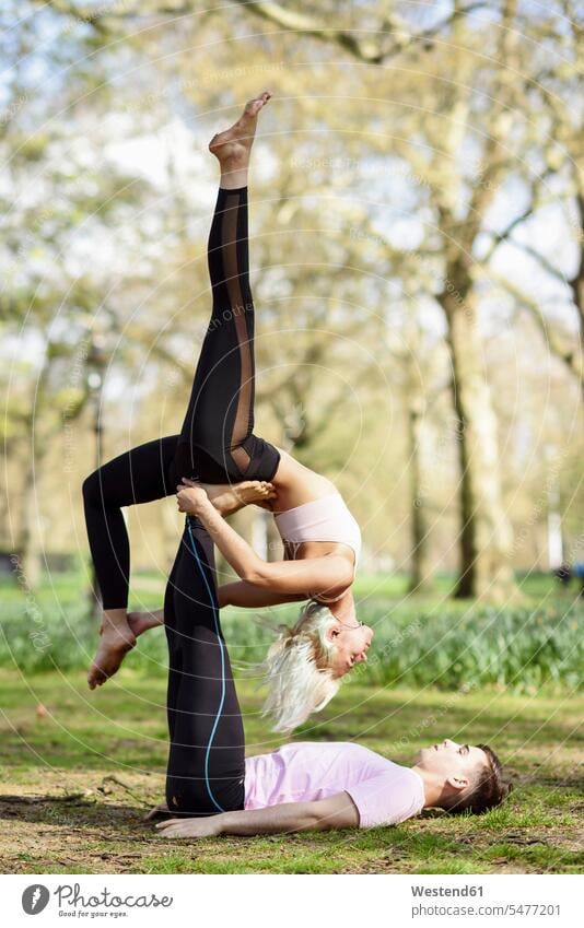 Junges Paar macht Yoga-Akrobatik in einem Stadtpark England Workout Übung Uebung Übungen Uebungen sportlich Gemeinsamkeit zusammen gemeinsam Ausgeglichenheit