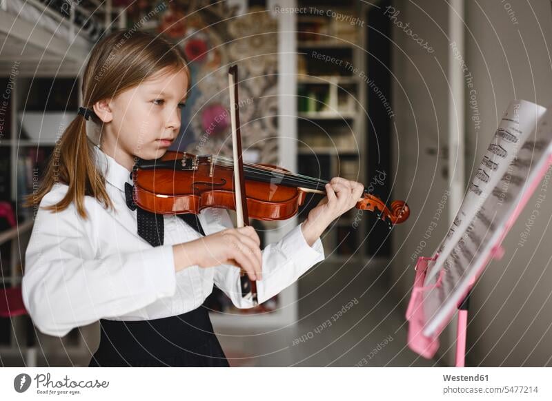 Mädchen spielt Geige Blick auf Notenständer zu Hause Violine Geigen Violinen Notenpult Notenstaender Notenpulte musizieren Musik machen Geigenbogen Bogen