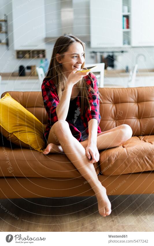 Glückliche junge Frau, die zu Hause auf einer Couch telefoniert Leute Menschen People Person Personen Alleinstehende Alleinstehender Singles Unverheiratete