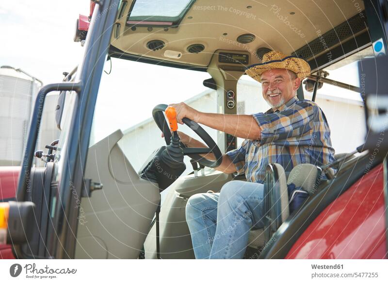 Porträt eines lächelnden älteren Landwirts auf einem Traktor Bauer Landwirte Bauern Senior ältere Männer älterer Mann Senioren Schlepper Traktoren Trecker
