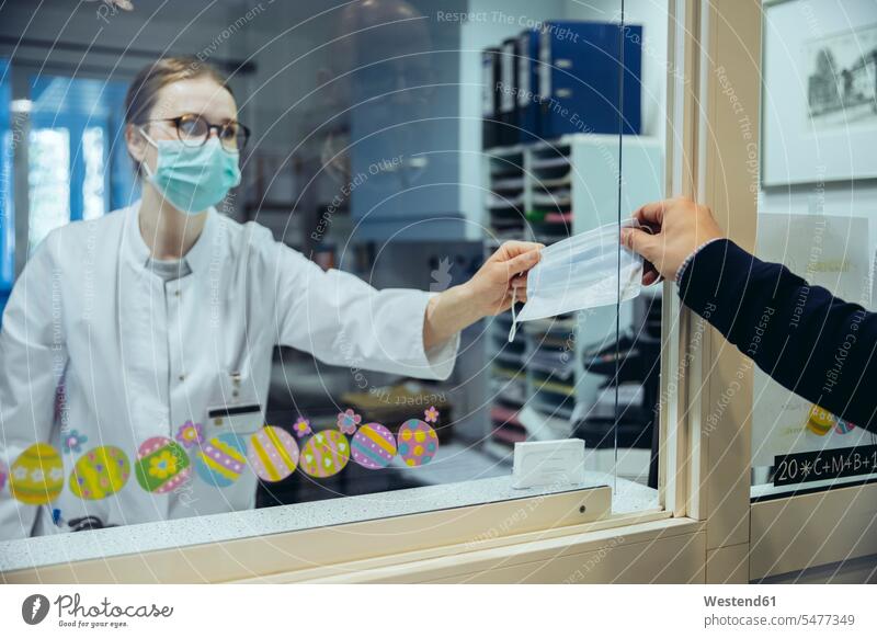 Angestellter am Empfangsschalter der Krankenhausstation übergibt Maske an Besucher Gesundheit Gesundheitswesen medizinisch Erkrankung Erkrankungen Krankheiten