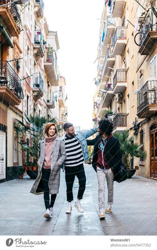 Drei glückliche Freunde beim Spaziergang in der Stadt staedtisch städtisch Glück glücklich sein glücklichsein gehen gehend geht Freundschaft Kameradschaft
