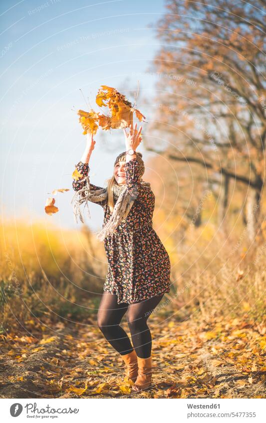 Glückliche schwangere Frau steht auf Waldweg spielen mit Herbstlaub glücklich glücklich sein glücklichsein Herbstblatt Herbstblaetter Herbstblätter stehen